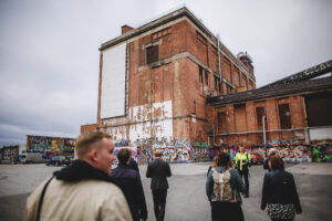 Joukko ihmisiä kävelee tiilirakennusta kohti.